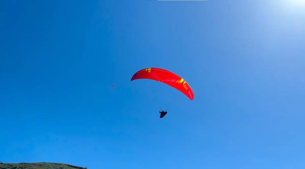 Red paraglider against a clear blue sky