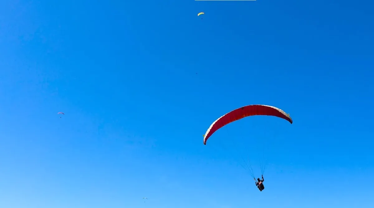 Paragliders on the launch field, with tents and people ready for their flights