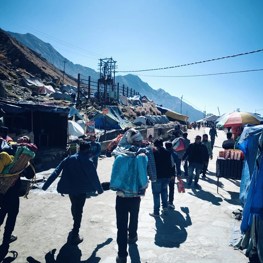 Veiw of Pitthu carring a person near kedarnath temple. Clear sky says it's the best time to visit to Kedarnath temple