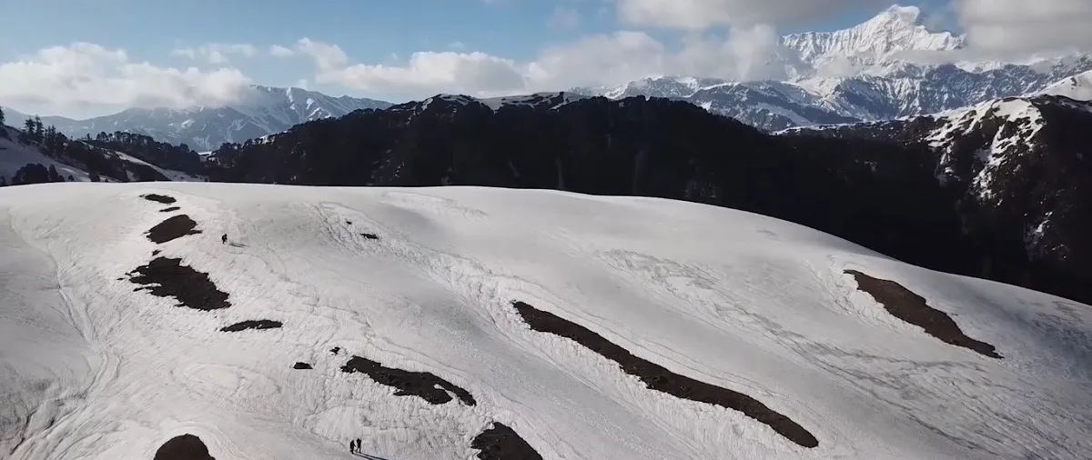 wide snow-covered slopes of Dayara Bugyal meadow with Himalayan peaks behind