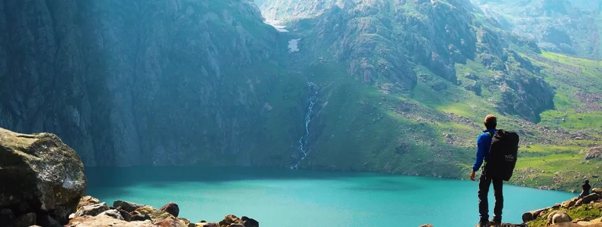 trekker standing above a turquoise alpine lake on the Kashmir Great Lakes trek