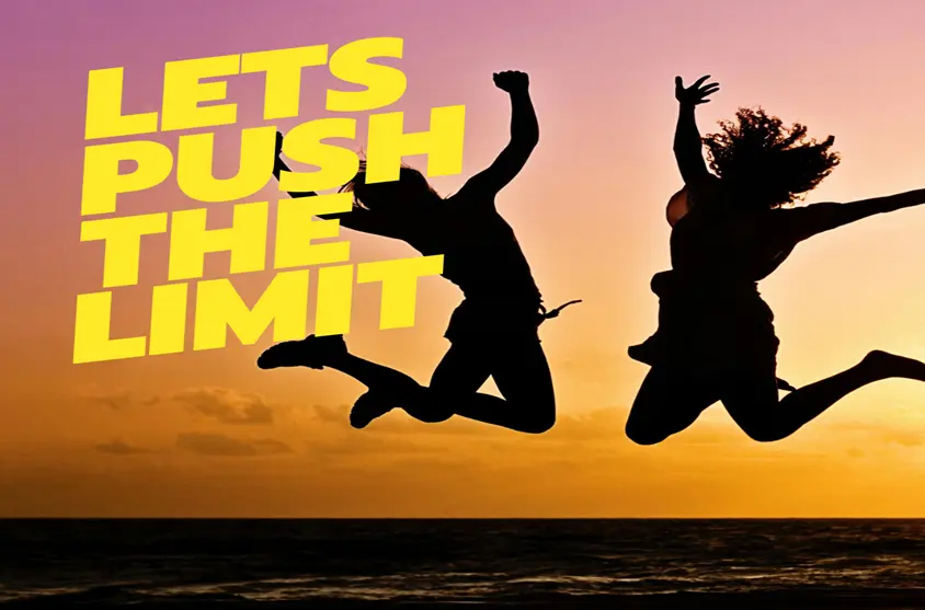 Two girls jumping with excitement with sunset in the background and the text let's push the limit to show the Kedarnath tour tips and Tricks