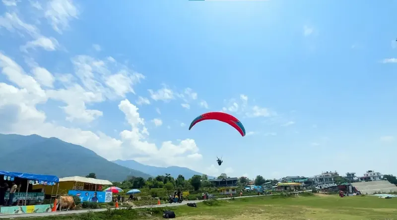 Paragliders in a blue sky above the Bir landing site