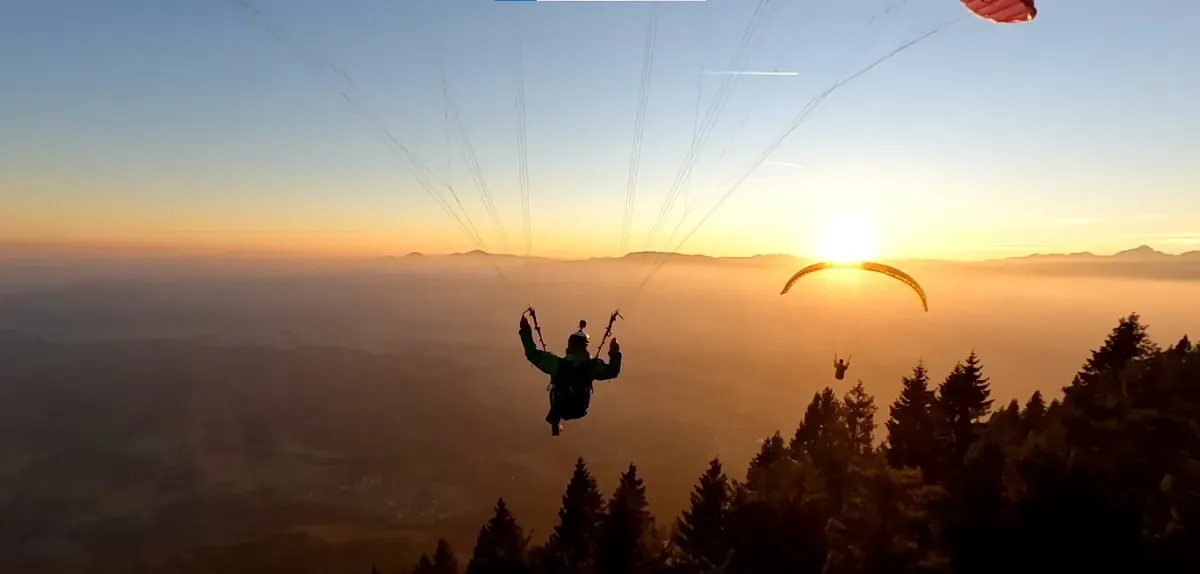 Paraglider silhouetted against the sunset over the Bir valley