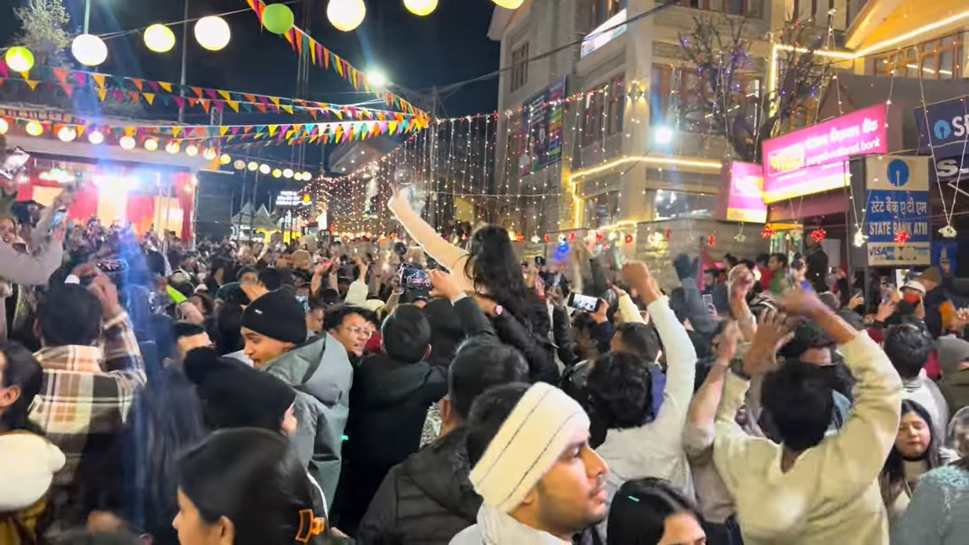 Crowd celebrating New Year's Eve on Manali Mall Road under festive lights