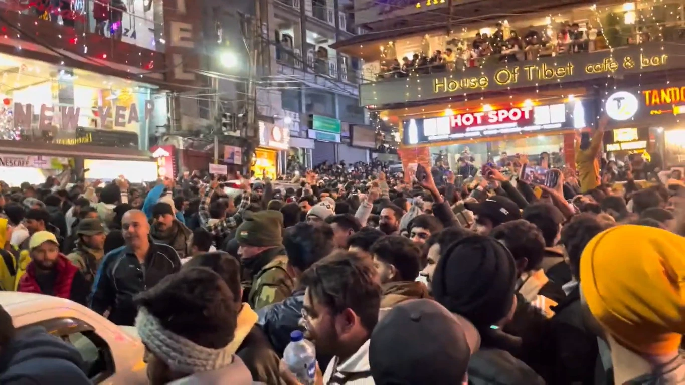 Crowds celebrating New Year's Eve in the main square of McLeodganj in front of lit-up cafés