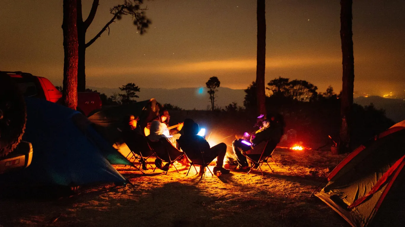 Friends sitting around a bonfire at a forest campsite at night, a peaceful New Year celebration in Lansdowne