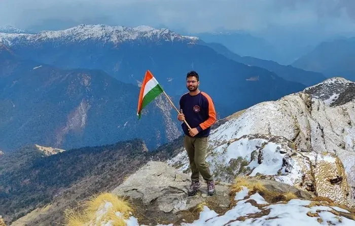 Trekker holding the Indian flag on the snowy ridge near Chandrashila