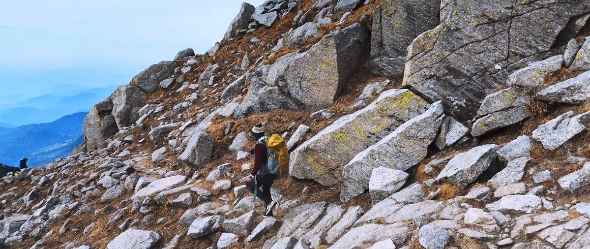 trekker climbing the rocky boulder trail to Laka Glacier above Triund