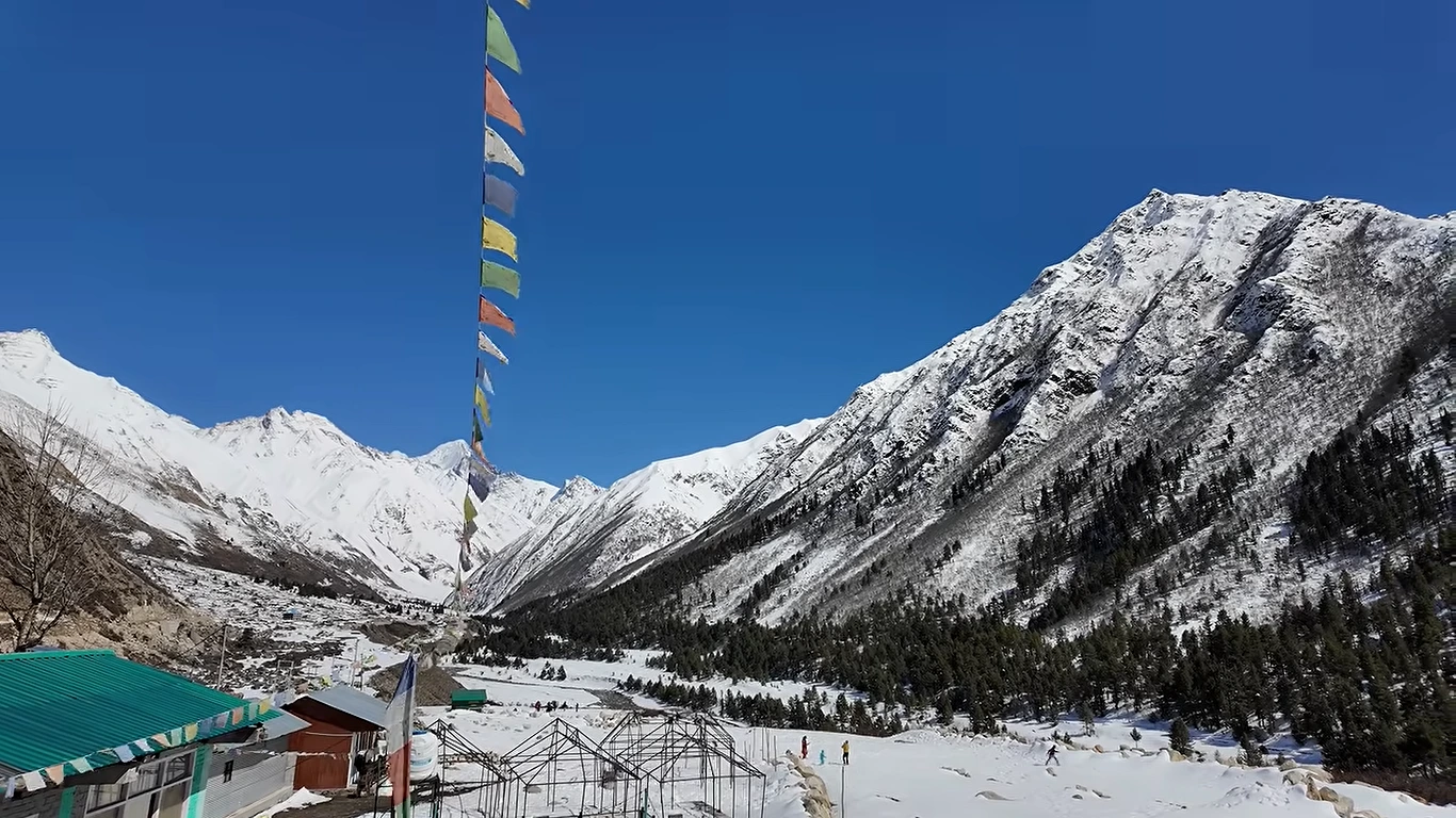 Snow-covered meadow with prayer flags and mountains in the Kinnaur Valley