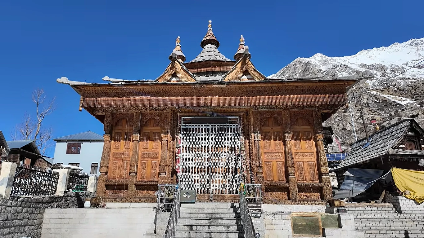 Carved wooden Mathi Devi temple with snow-capped peaks behind, near Chitkul