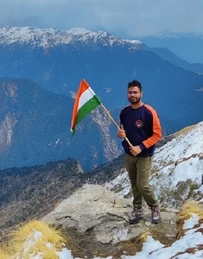 A man holding a indian flag at the peak of chopta tungnath trek