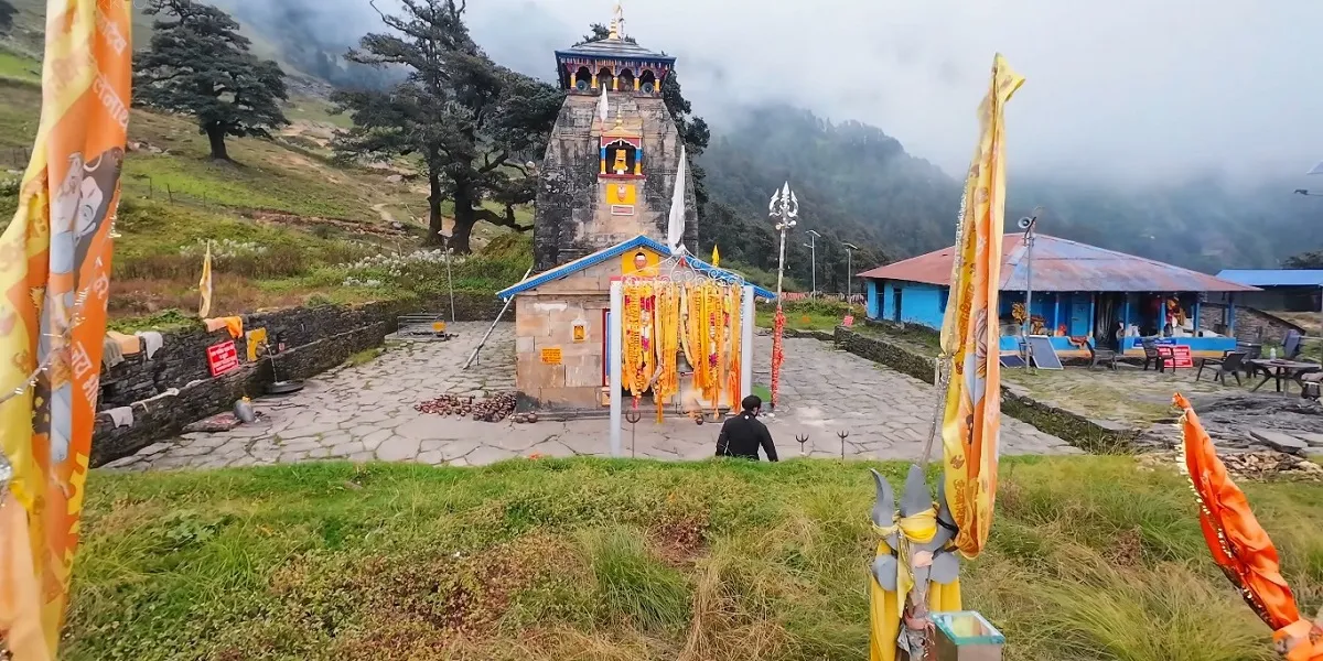 Madhyamaheshwar Temple with saffron flags and offerings in the misty Garhwal Himalayas