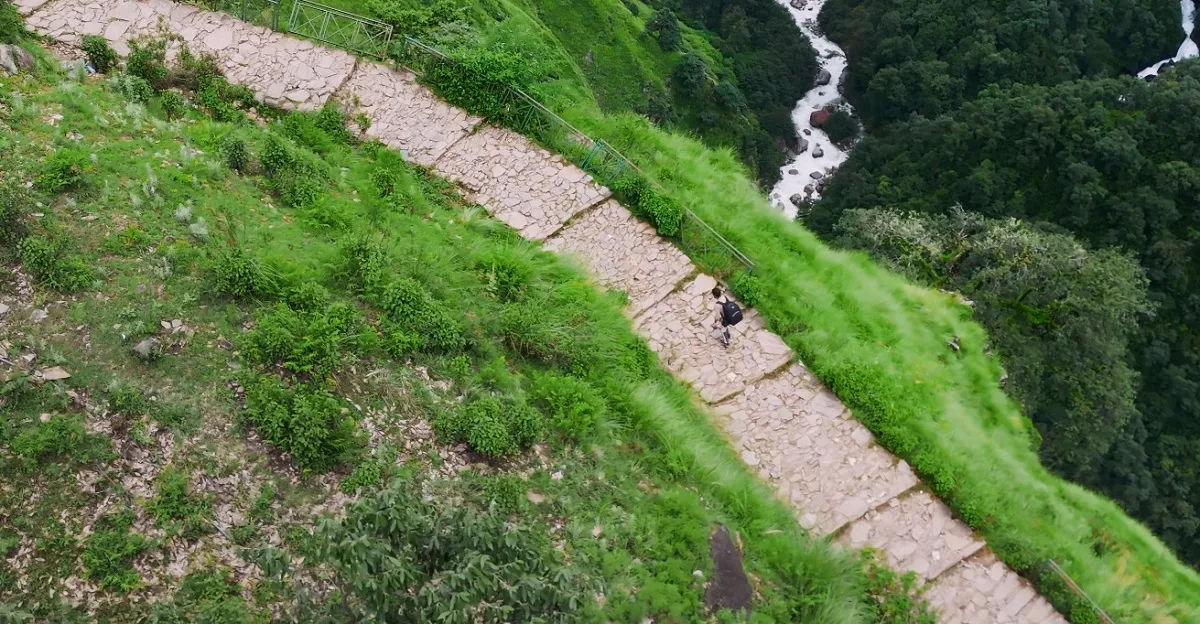 Stone-paved steps of the Madhyamaheshwar trek above a river gorge, on the descent to Ransi