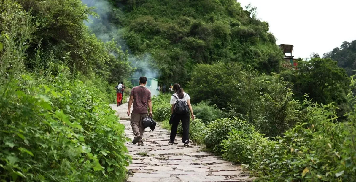 Trekkers walking a stone-paved forest path from Ransi towards Madhyamaheshwar