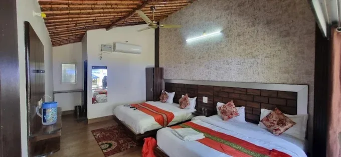 Room at Nakshatra Resort with two double beds, wooden ceiling and air conditioner