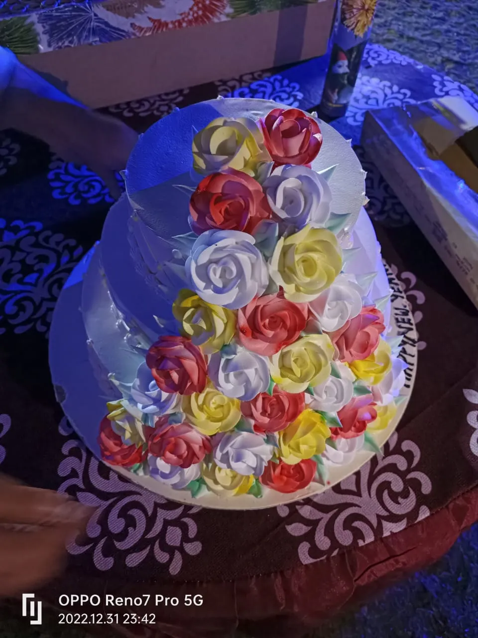 Two-tier New Year cake decorated with red, white and yellow roses for the midnight cake cutting