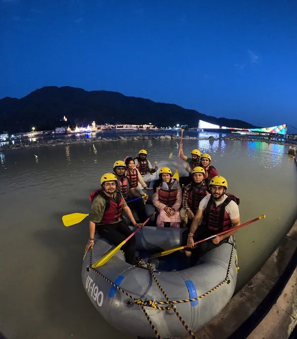 Group of rafters in helmets and life jackets in a raft on the Ganga in Rishikesh at dusk