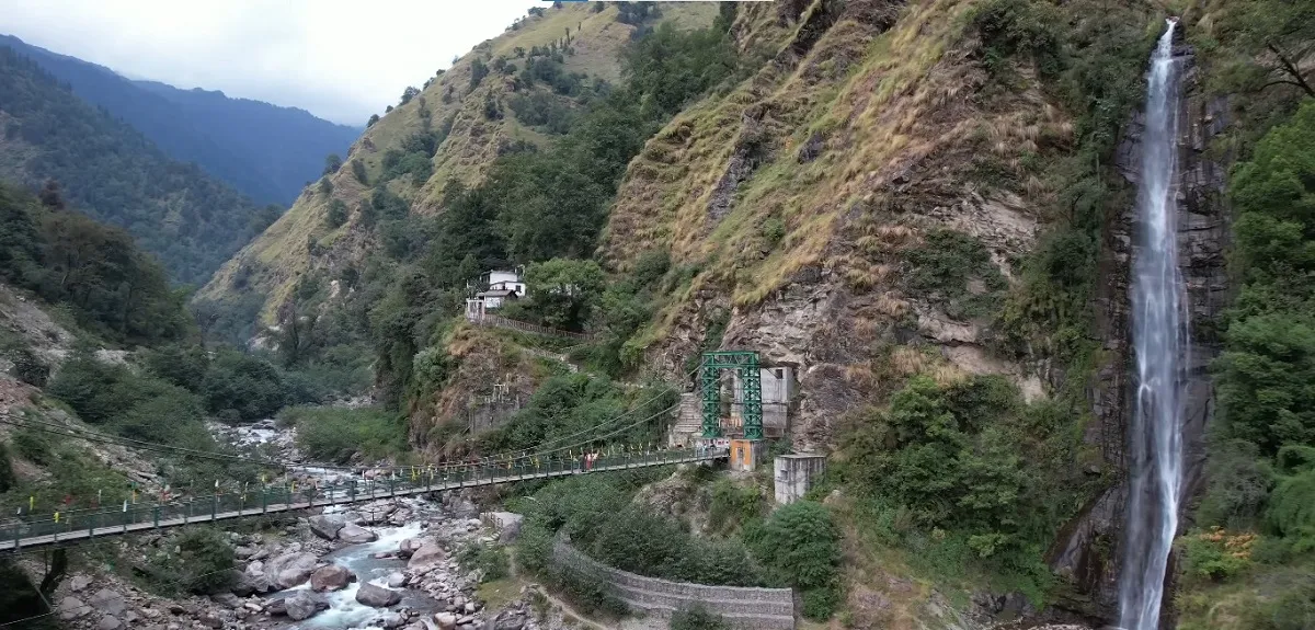 Green Urgam valley with a waterfall and a footbridge over the stream on the way to Kalpeshwar