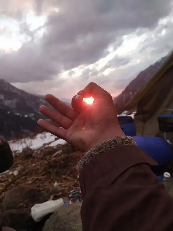 A trekker on Laka Glacier trek posing with sun at summit of triund laka glacier trek