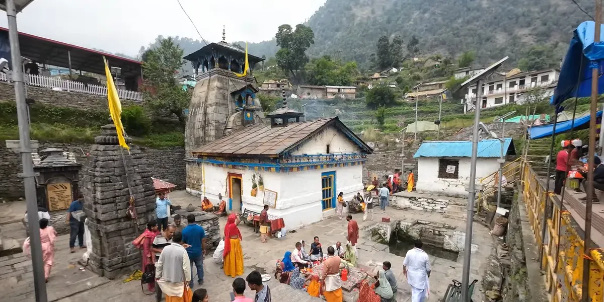 Triyuginarayan Temple in Uttarakhand with pilgrims in the courtyard and green hills behind